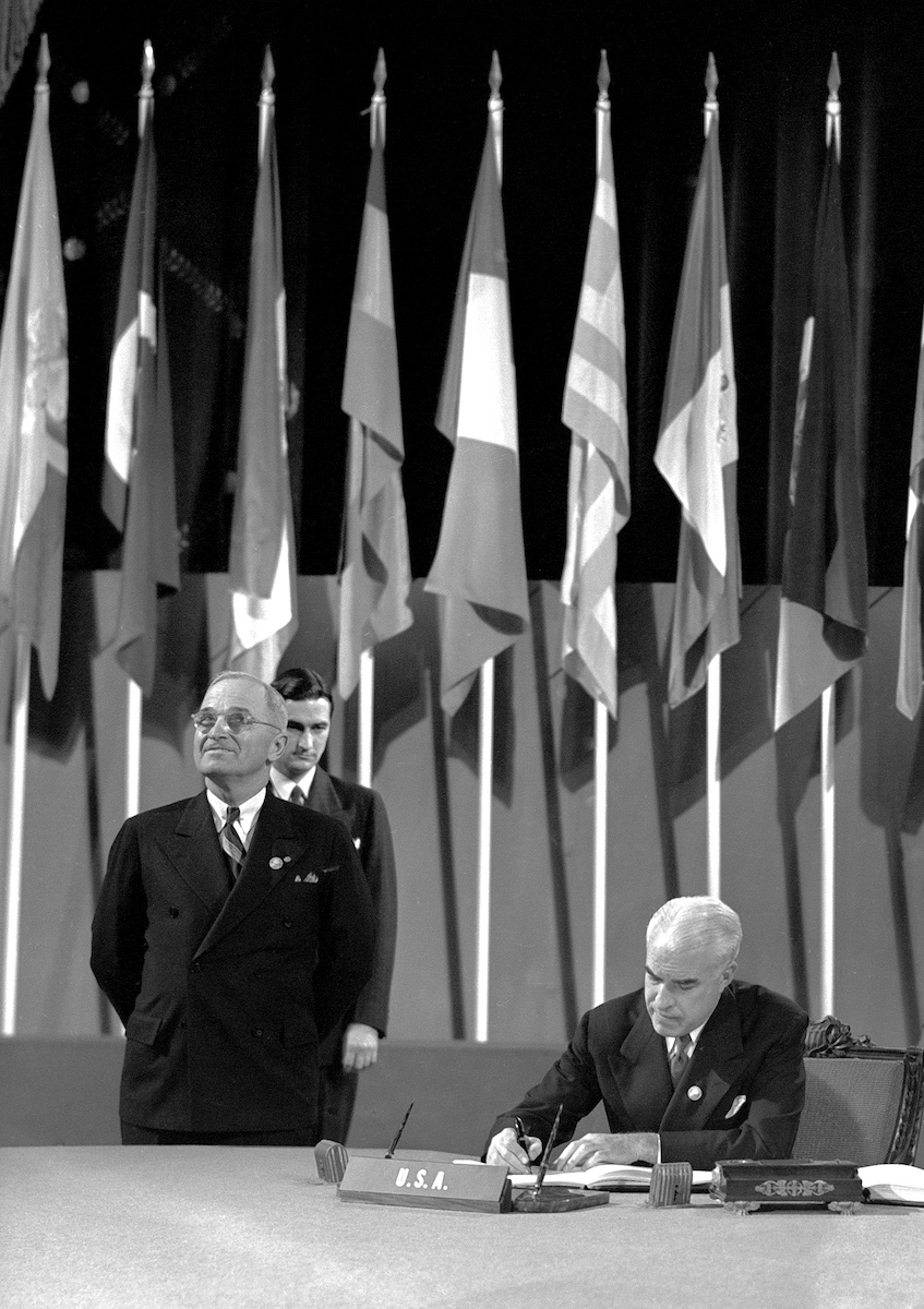Edward Stettinius signing the UN Charter on 26 June 1945, as President Truman stands at left.