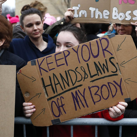 Women at the Women's March in DC with signs: "Can't Believe We STILL Have to Protest", "Keep your Hands and Laws Off my Body", "RAPE CULTURE" with a line through it
