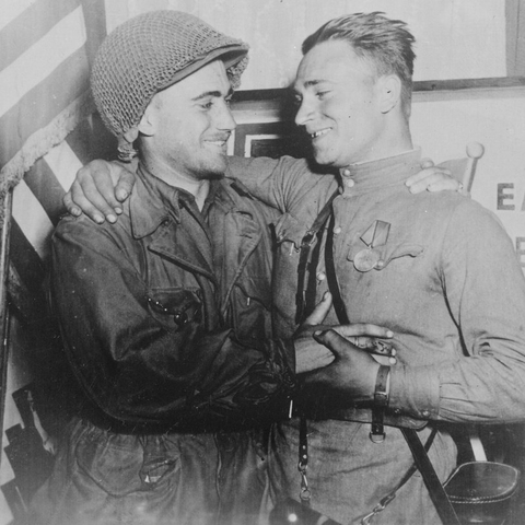 Happy 2nd Lieutenant William Robertson and Lt. Alexander Sylvashko, Soviet Army, shown in front of sign [East Meets West] symbolizing the historic meeting of the Soviet and American Armies, near Torgau, Germany, 1945.