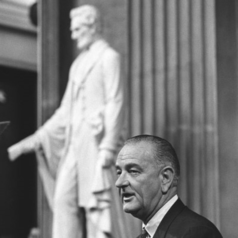 President Lyndon B. Johnson giving a speech about the Voting Rights Act with a statute of President Abraham Lincoln in the background.
