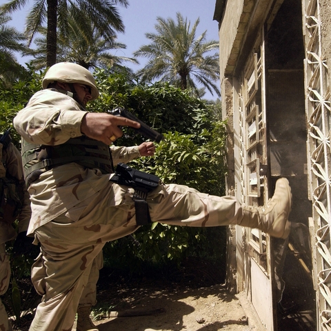 A contractor for the U.S. Army kicking in a door during Operation IRAQI FREEDOM.