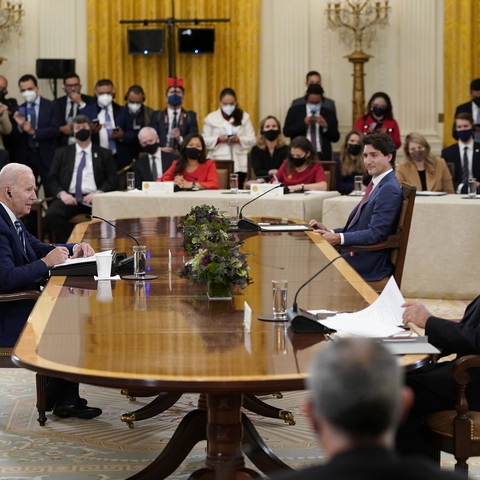 President Joe Biden with other foreign leaders, sitting around a table with others looking on