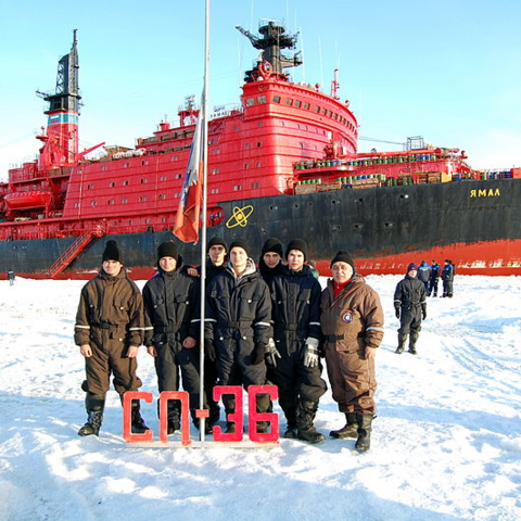 "North Pole 36" personnel pose in front of a nuclear-powered icebreaking ship.
