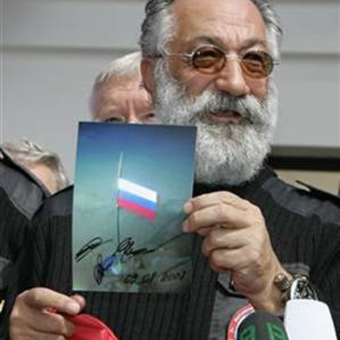 At a press conference, Artur Chilingarov holds a photo of the Russian flag his exploration team planted underwater at the North Pole.