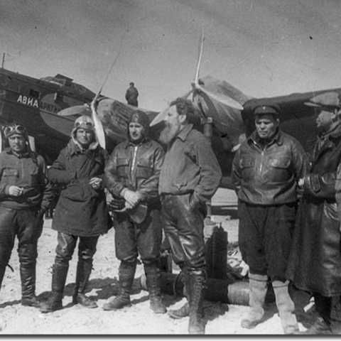 Participants of the North Pole-1 expedition. Otto Shmidt is in the middle, with one of the airplanes that they landed at the North Pole.
