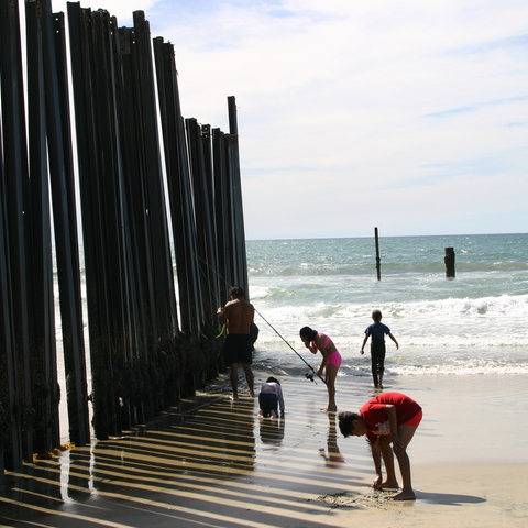 A Mexican family enjoying the beach on the U.S. side of the border fence