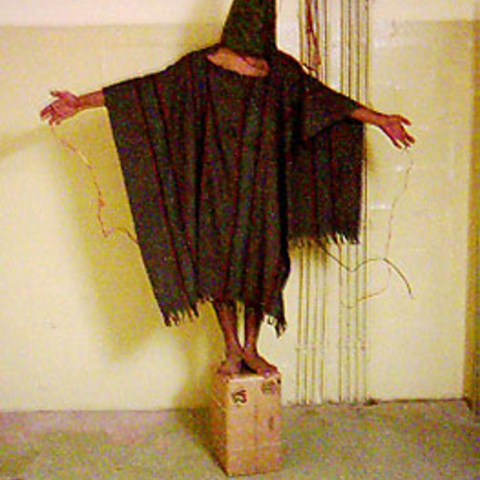 An Iraqi prisoner attached to electrical shocking devices at Abu Ghraib