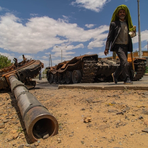 A man passes by a destroyed tank in Edaga Hamus.