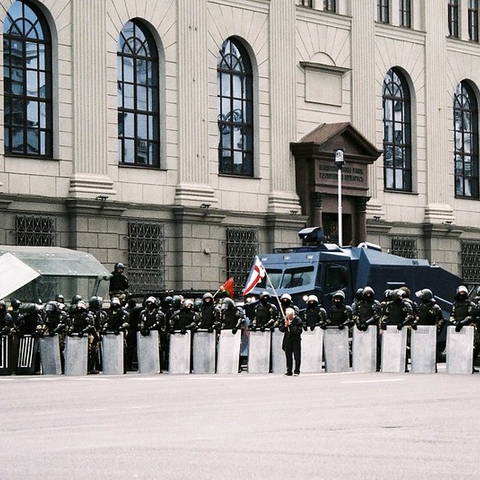 A lone protestor holds the BNR flag in front of a police line in Minsk.