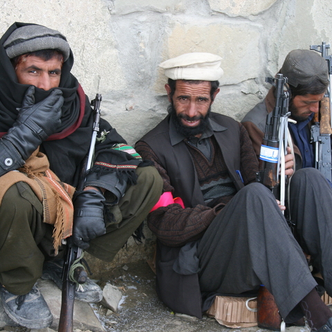 Three Afghan police trainees, sitting on ground with guns