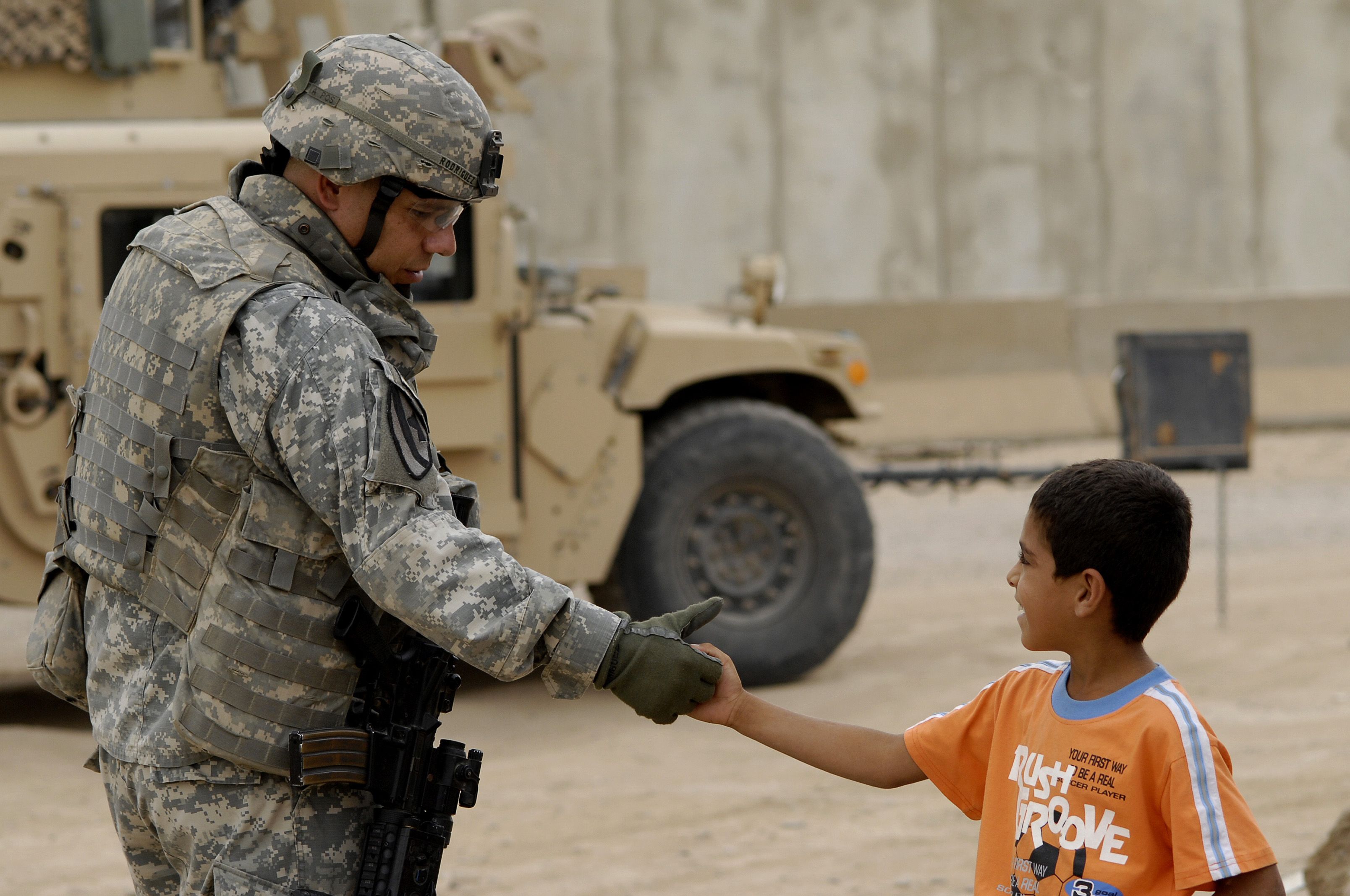 U.S. Army Maj. Robert Rodriguez shakes hands with a local child.