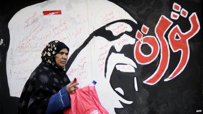 A woman walks by revolutionary graffiti in Cairo.