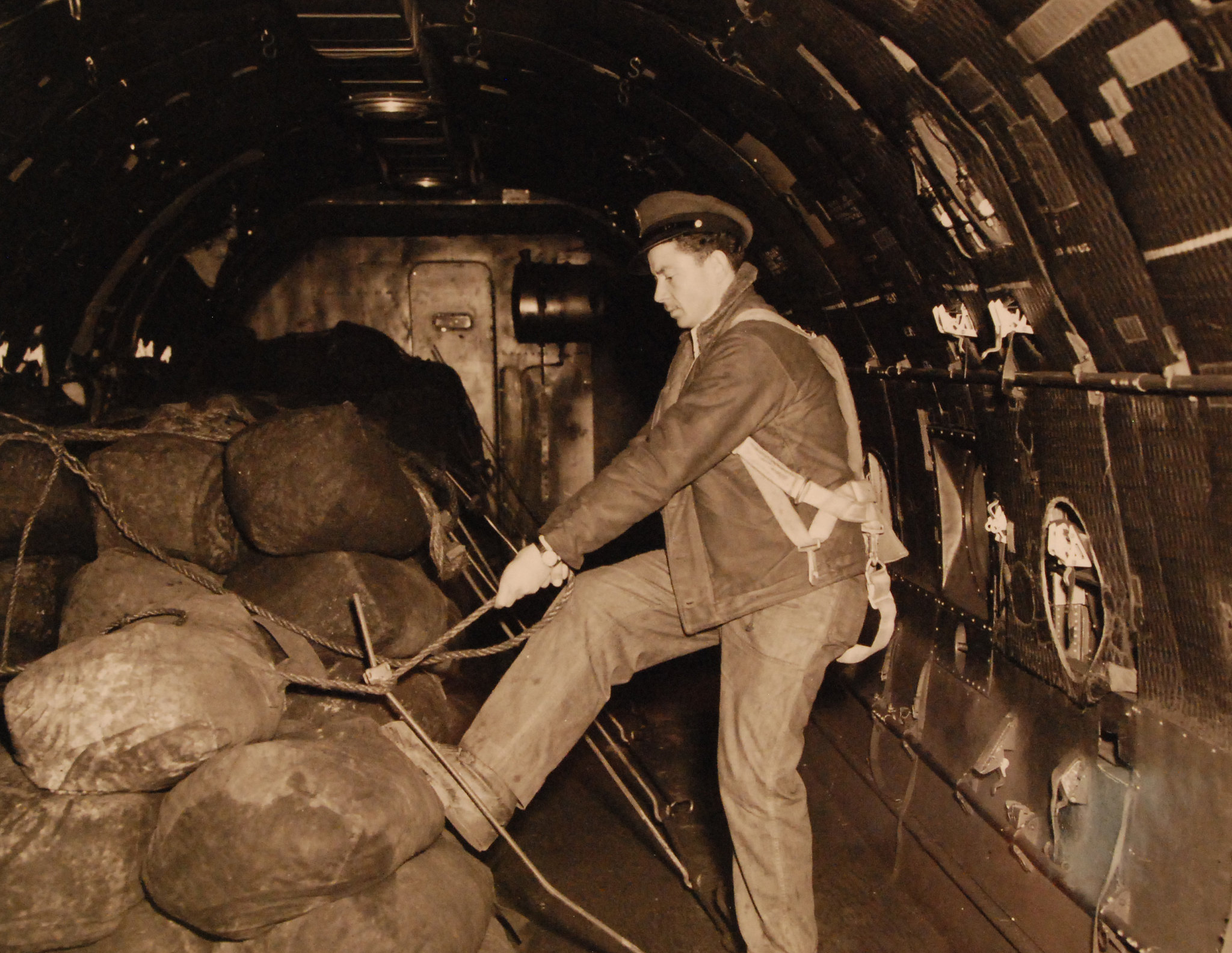 An American flight mechanic checks the latches on bags of coal to be delivered during the Berlin Airlift.