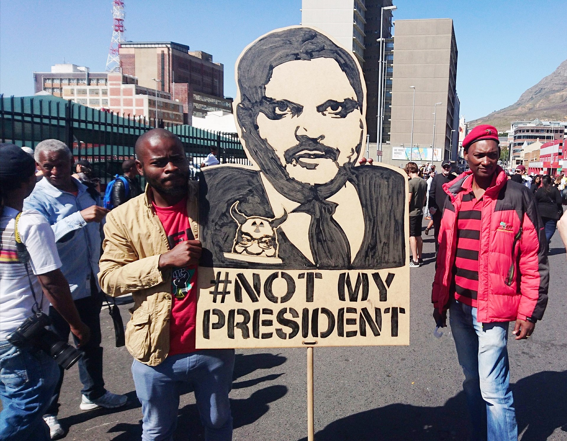 Protesters at a 2017 'Zuma Must Fall' rally in Cape Town with a depiction of Atul Gupta.