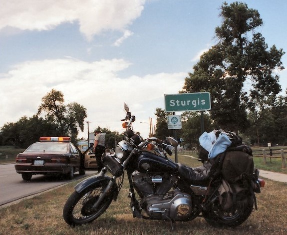 A motorcycle parked in front of the Sturgis city limit sign. (Image by Chris Heald)