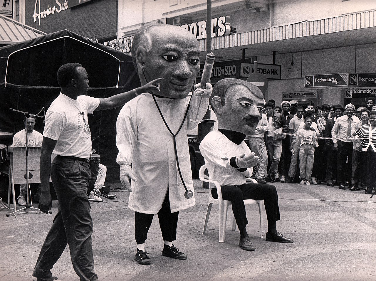 World AIDS Day Performance of Puppets Against AIDS. A puppeteer playing a doctor is drawing blood from Joe, the protagonist of the puppet show, to see if Joe tests positive for HIV. Cape Town, South Africa, 1980s.