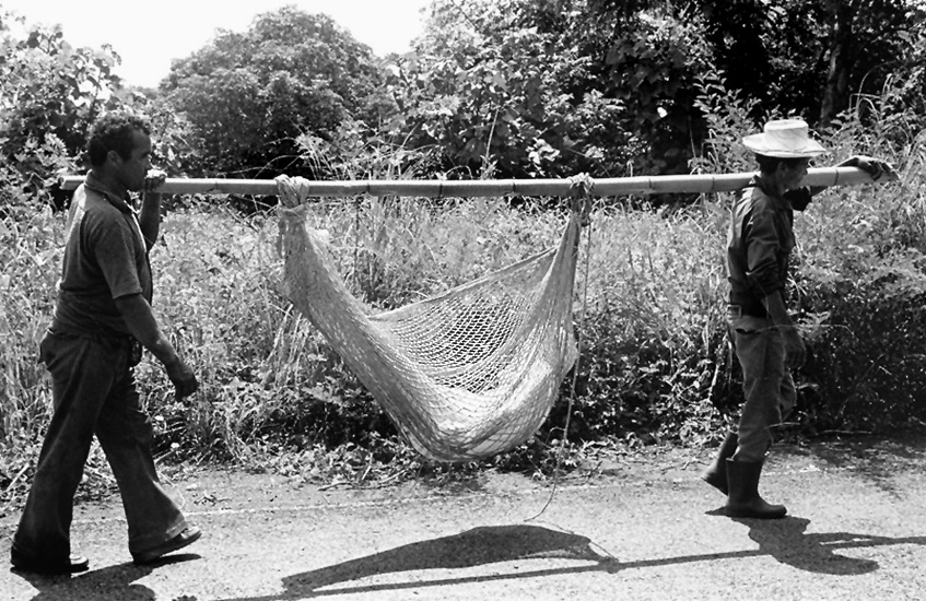A casualty of the Salvadoran Civil War is carried back to his farm for burial (1982). Photo by Gary Mark Smith.