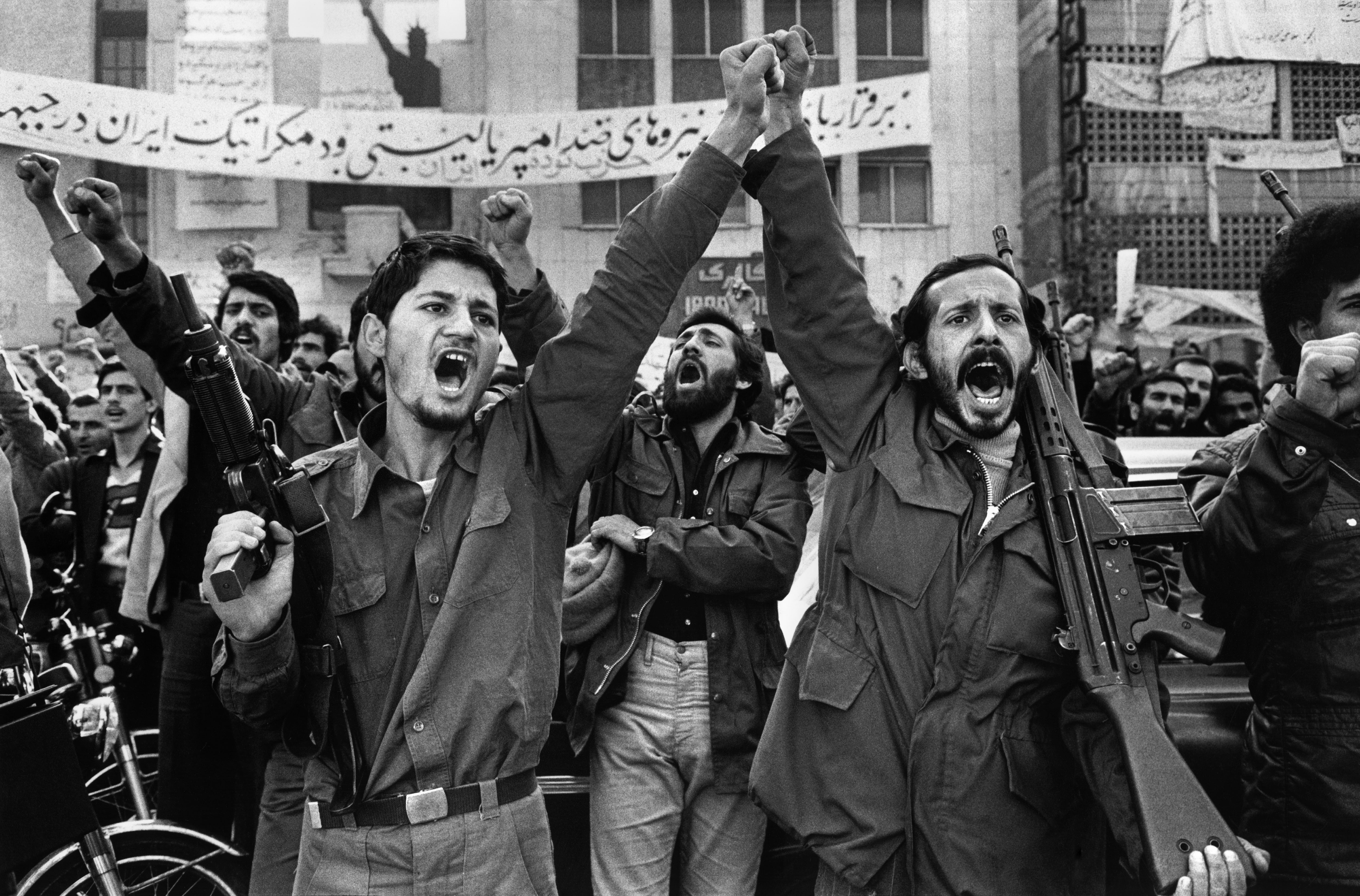 Two armed militants outside the Embassy of the United States in Tehran. Behind them is a banner that says: "Long live anti-imperialism and democratic forces", 1979.