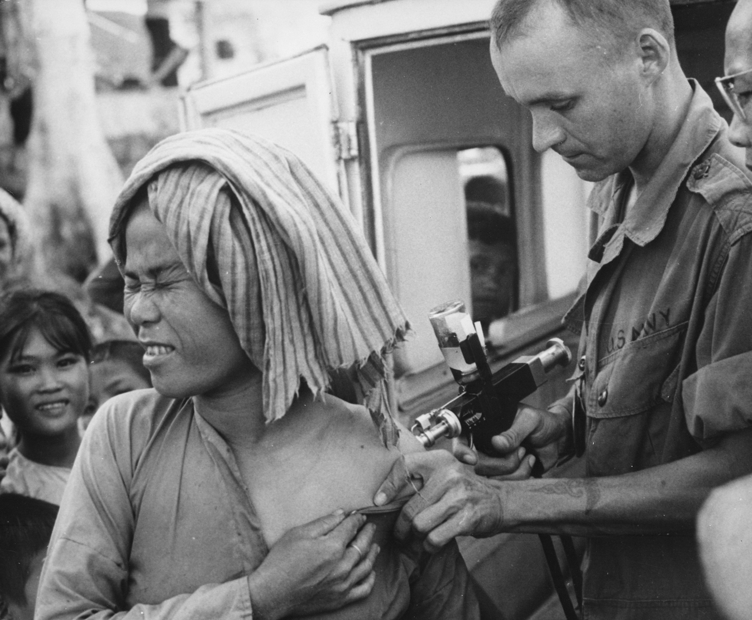 A U.S. Navy hospital corpsman, member of a USAID military health team, inoculates a flood refugee against cholera at the refugee center on Nui Sam mountain, Chau Doc province., 1966