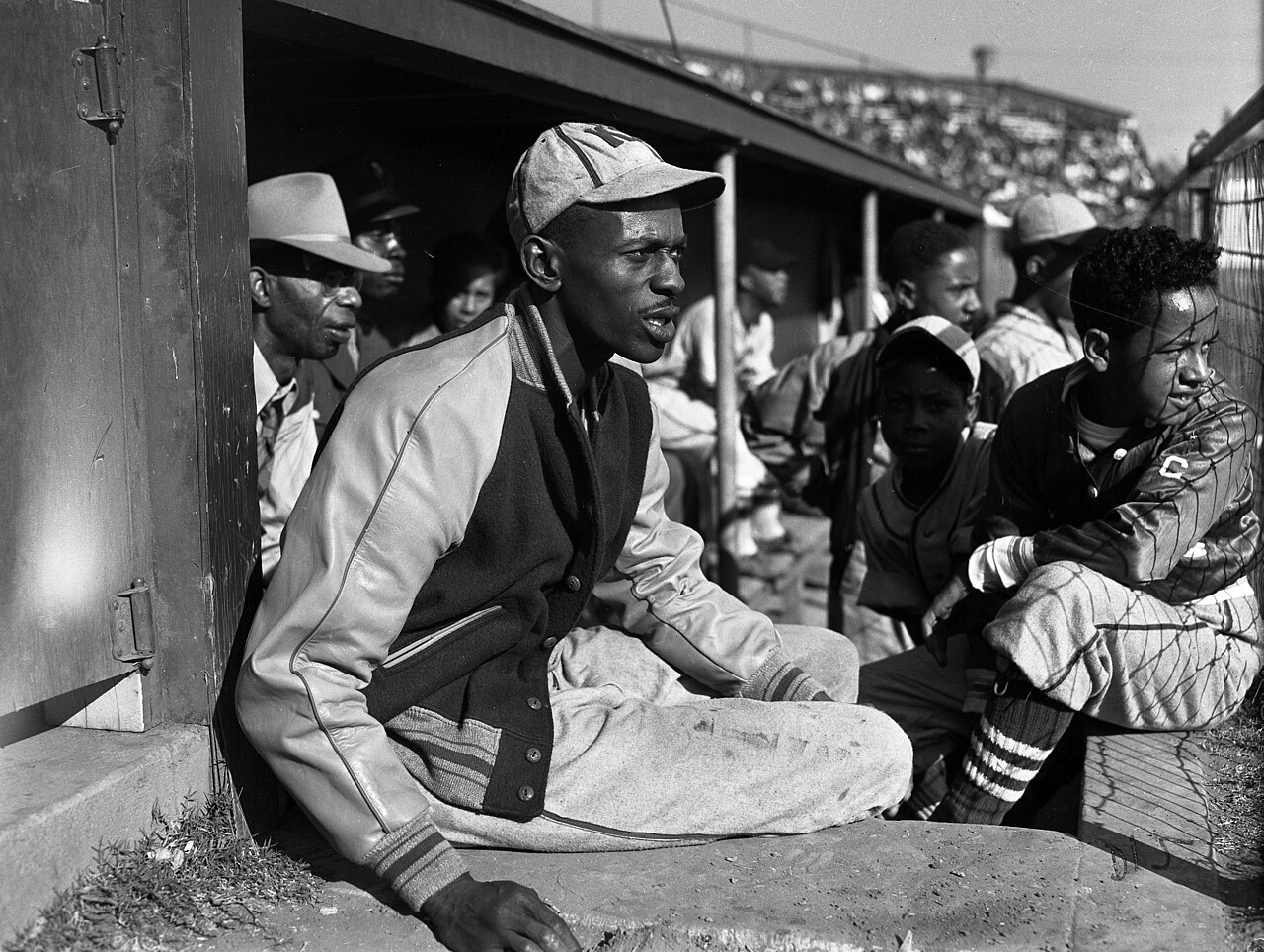 Satchel Paige with bat boys in dugout watching game in Los Angeles