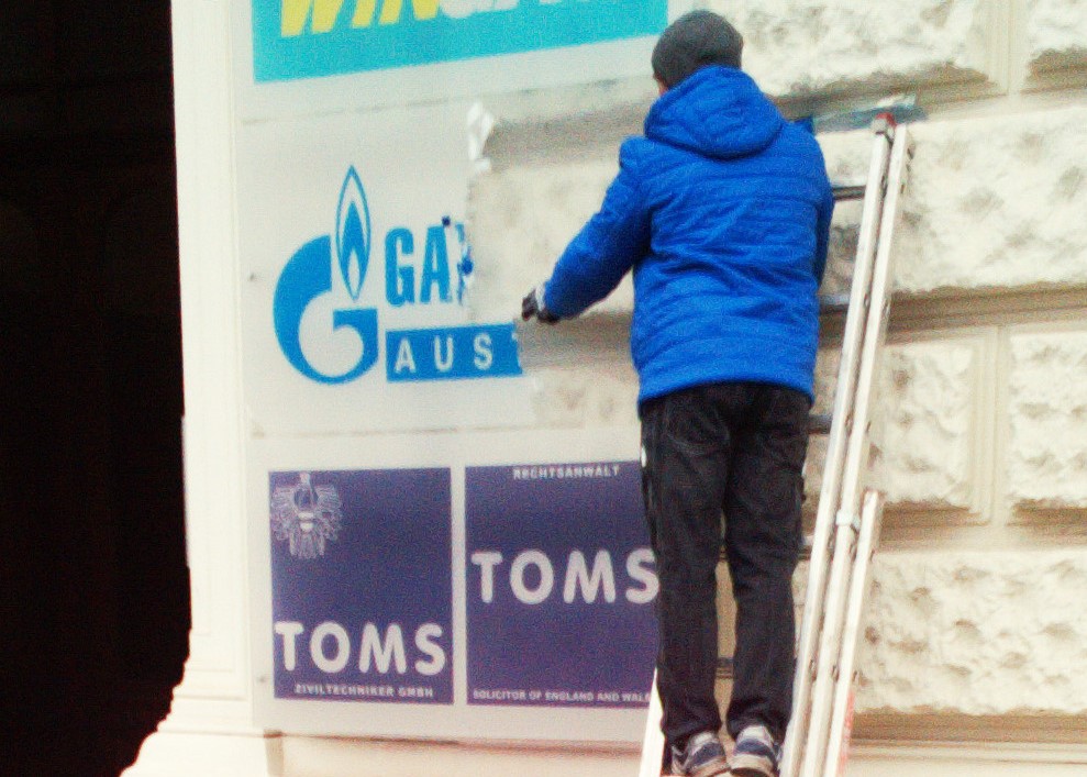A worker removes the sign from Russian company Gazprom's office in Vienna, 2022.