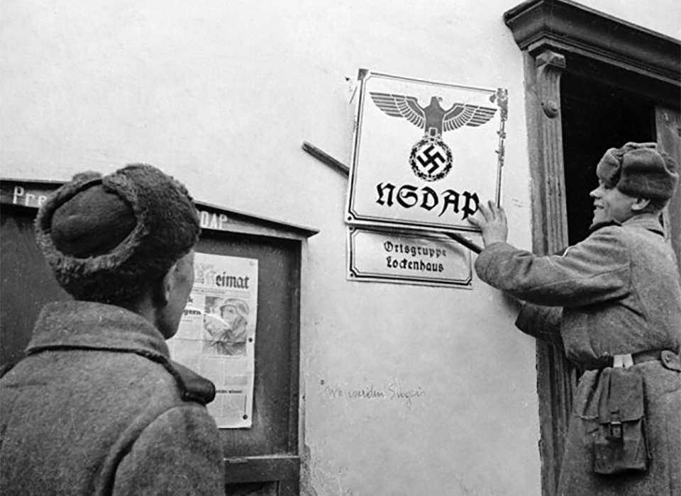 Soviet soldiers taking down a Nazi sign in Austria, 1945.