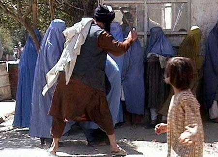 Two Taliban religious police beating a woman in public because she removed her burqa in public, Kabul, 2001.