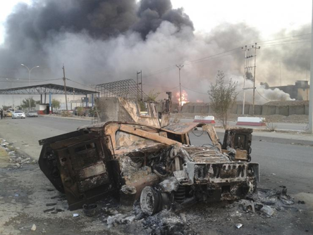 Mosul burns behind the remains of an American Humvee.