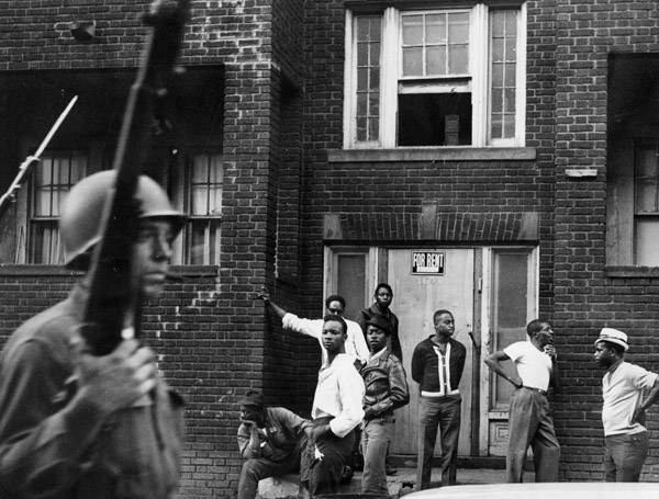 Ohio National Guard members patrol a Hough neighborhood as residents look on, 1966.