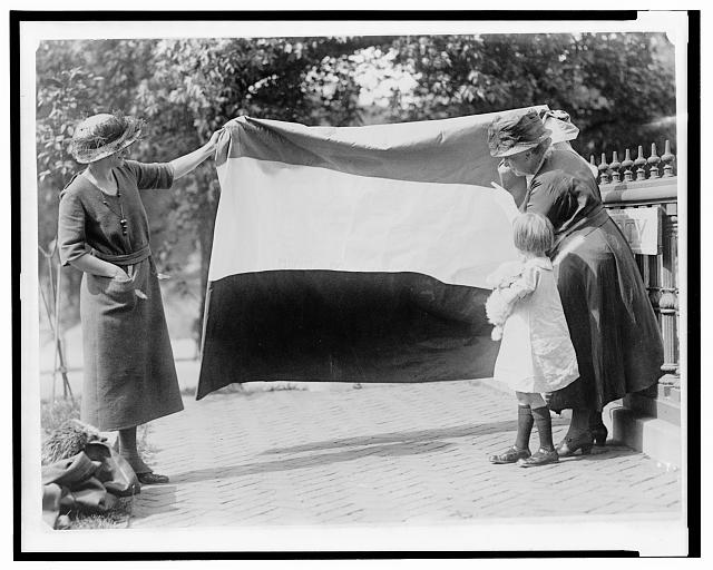 Two suffragists showing banner to young girl, c. 1910-1920.