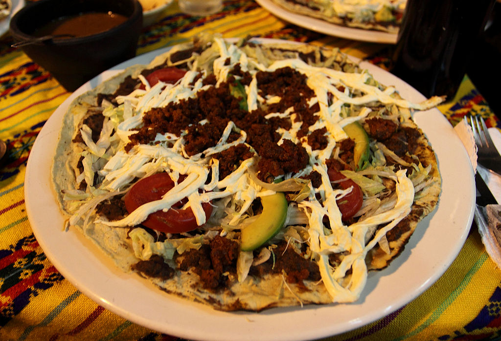 A tlayuda topped with Oaxaca cheese and chorizo.
