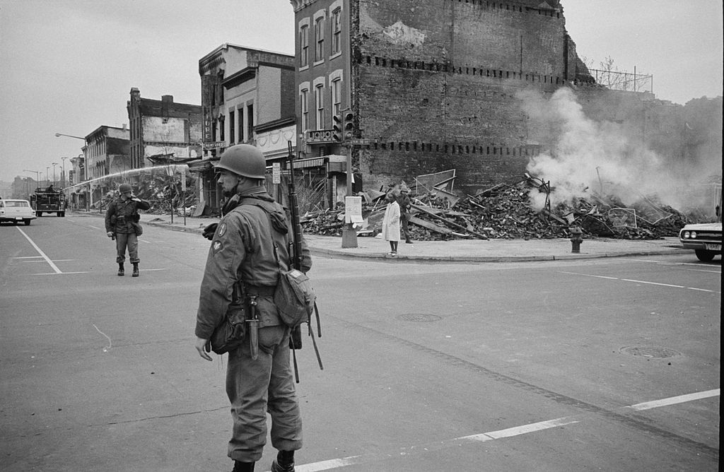 A soldier stands observing the aftermath of a race riot in Washington D.C., 1968, following the assassination of Martin Luther King, Jr.