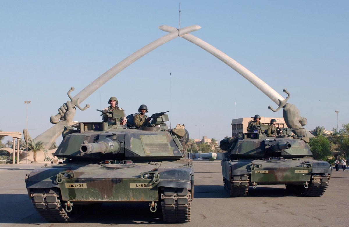 Members of the U.S. Army pose under the 'Hands of Victory' sculpture in Baghdad.