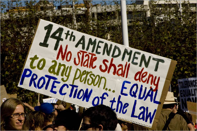 Protesters carry a sign highlighting the promise of equal protection to all people under the Fourteenth Amendment.