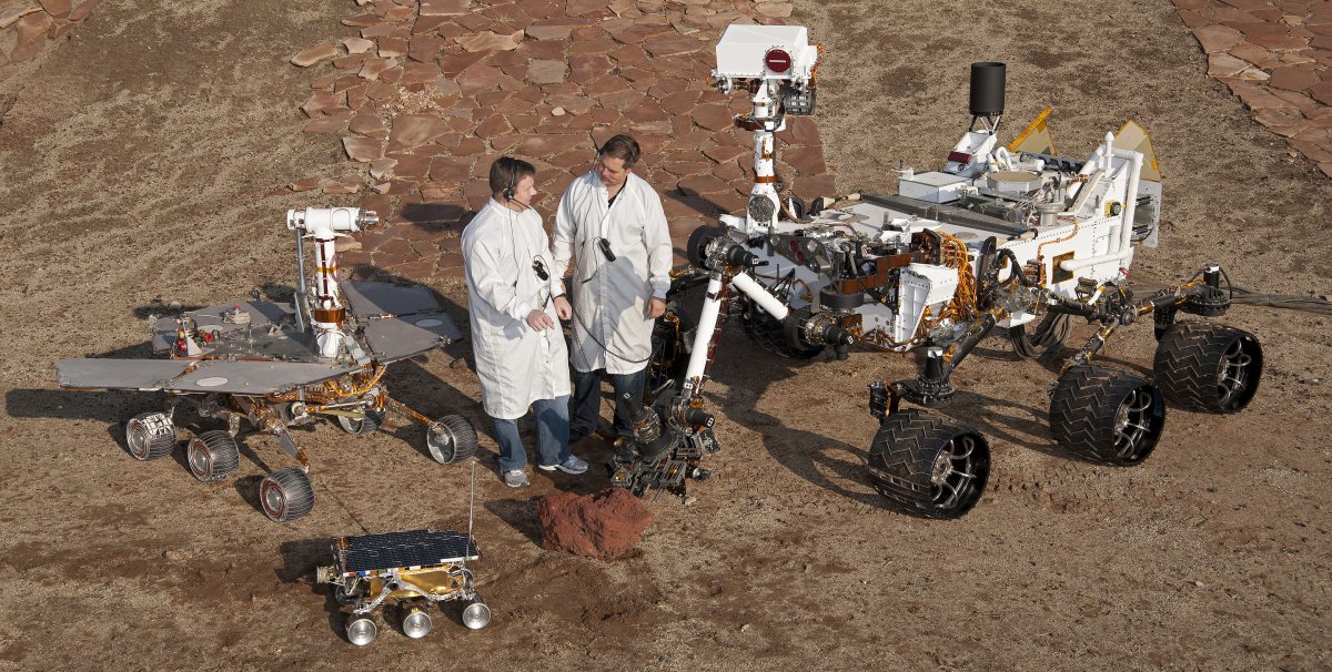 Engineers pose with test models of three generations of Mars explorers.