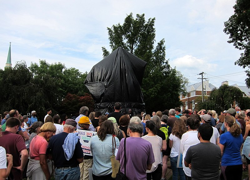 Participants in an August 28, 2017 March to Confront White Supremacy stand in front of a covered Robert E. Lee statue in Charlottesville, VA.