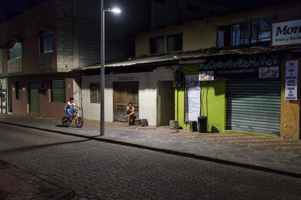 A boy biking down a street at night.