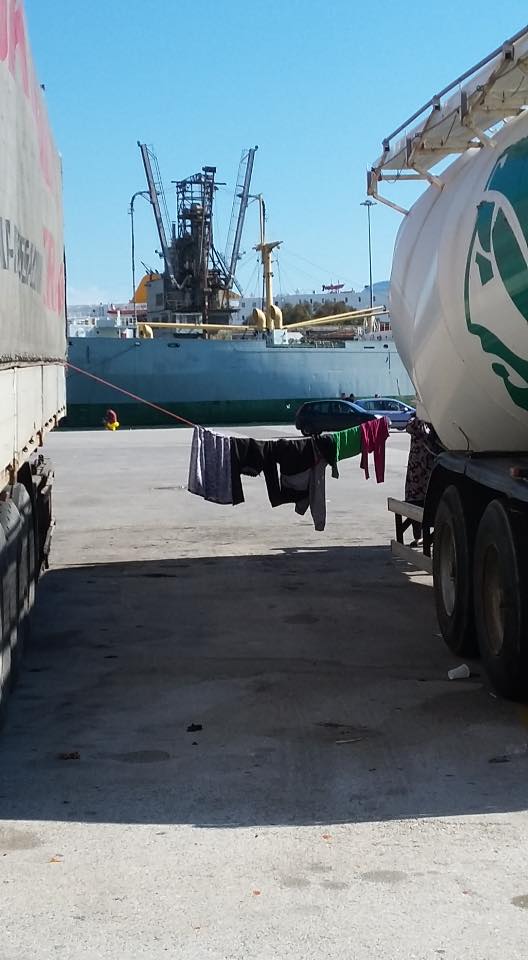 Laundry strung between two parked trucks in Piraeus.