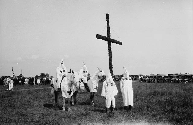 Ku Klux Klan members stand by a cross erected in a field near Kingston, Ontario.
