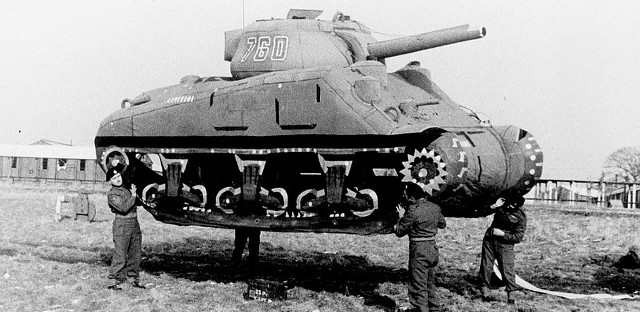 Allied soldiers hold aloft a dummy tank to deceive Germans.