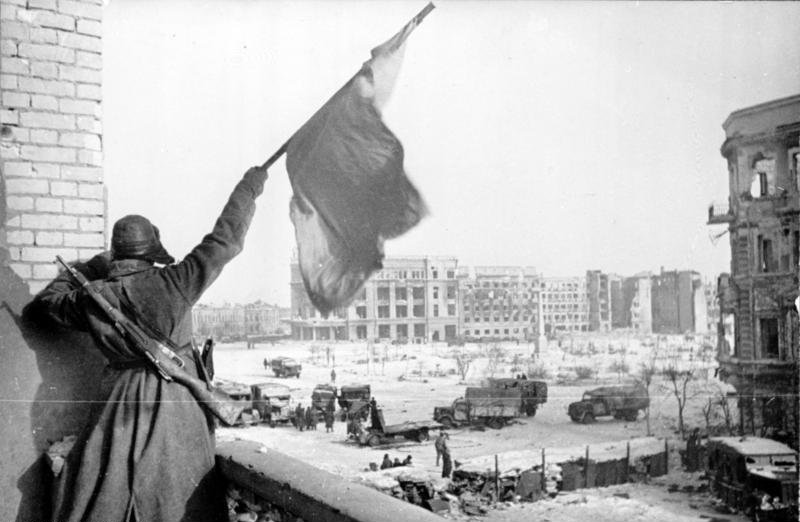 A Soviet soldier waves the Red Banner near the central plaza of Stalingrad, 1943