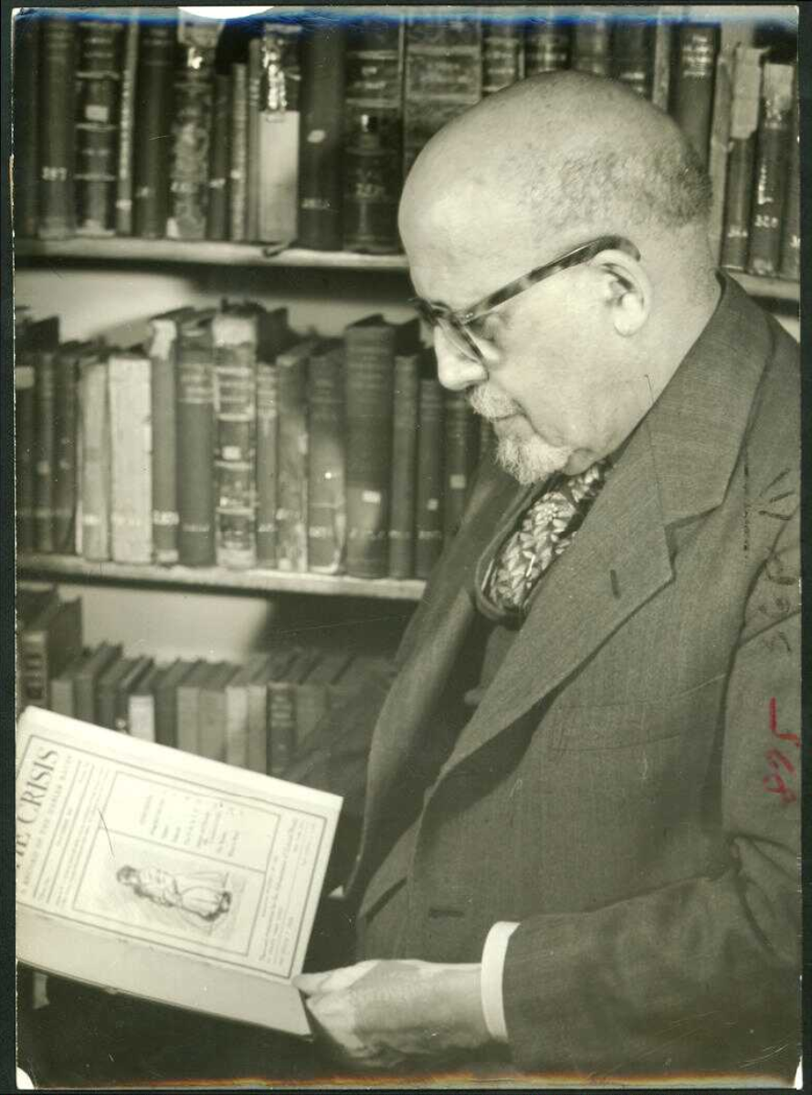 Du Bois in his office holding a copy of the first issue of The Crisis.