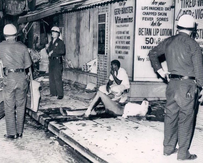 A man in bleeds on the sidewalk after he is shot by police in Watts on August 14, 1965