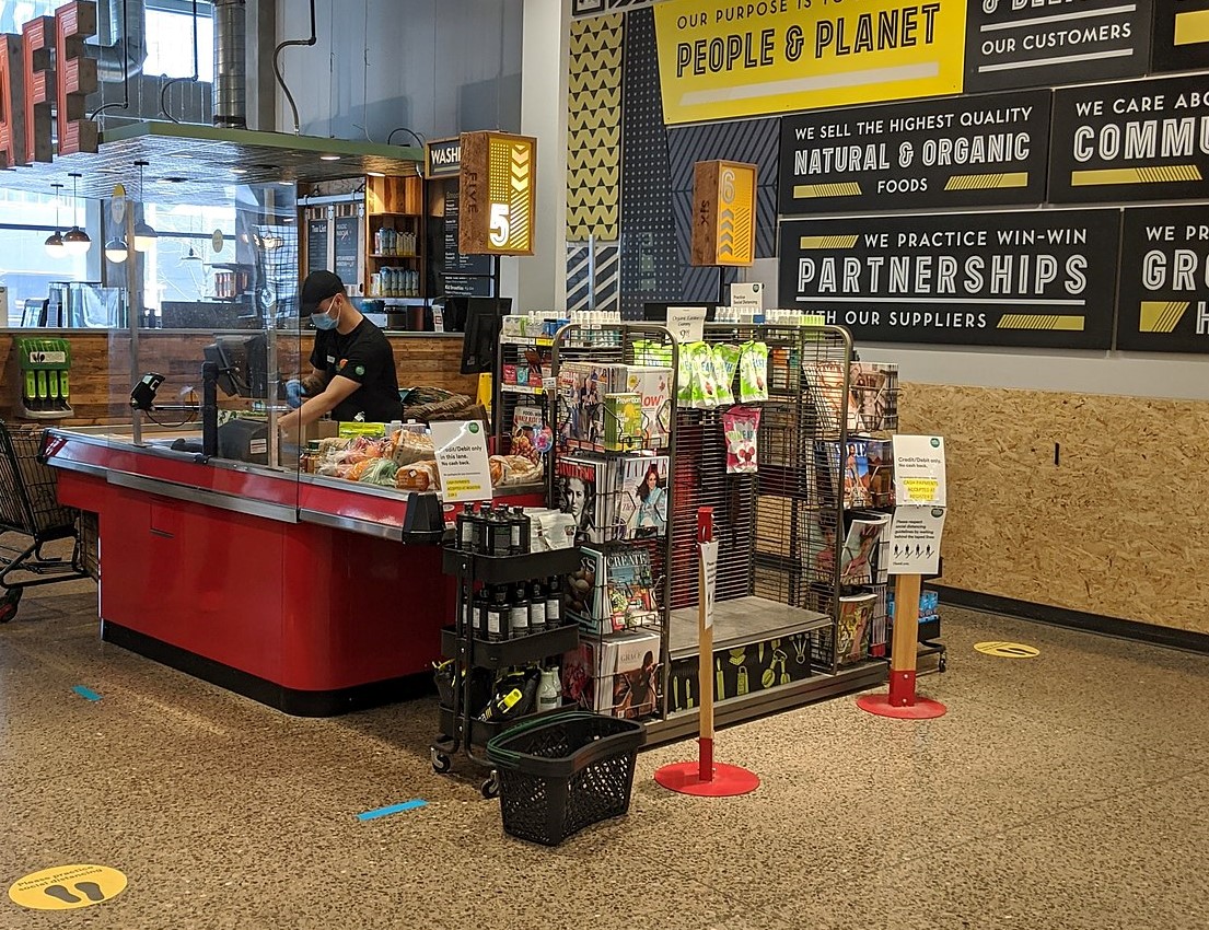 Social distancing markers and a plexiglass shield at Whole Foods Market checkout.