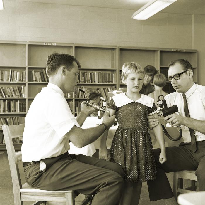 Two public health technicians carry out a vaccination campaign inside a Dekalb County, Georgia, elementary school, 1966.