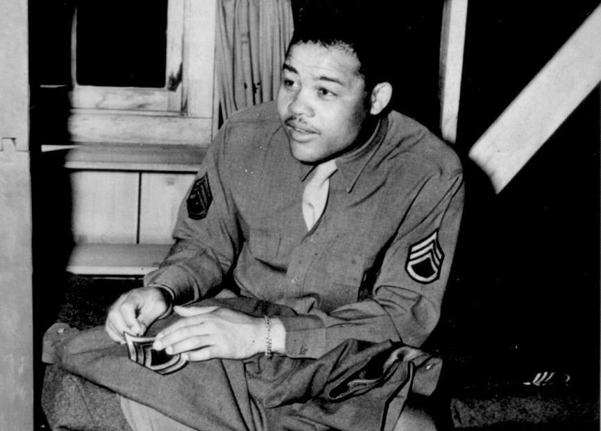 Joe Louis sews on the stripes of a technical sergeant to his army uniform, 1945
