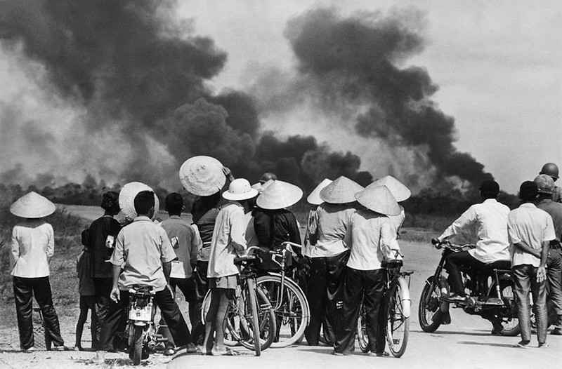 Vietnamese people watch an explosion during the Vietnam War.