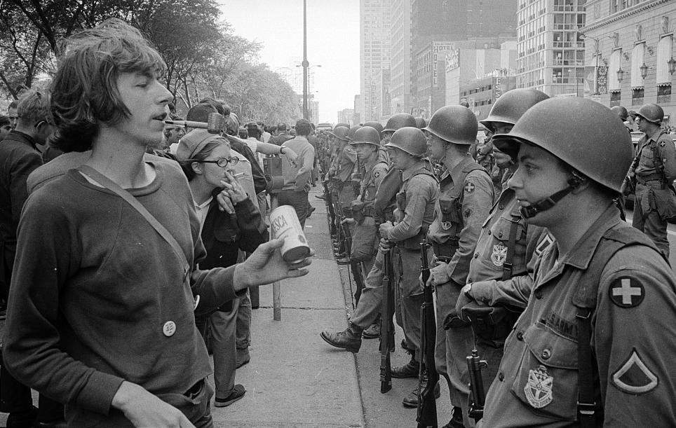 Protester standing in front of a row of National Guard soldiers, across the street from the Democratic National Convention in Chicago, 26 August 1968.