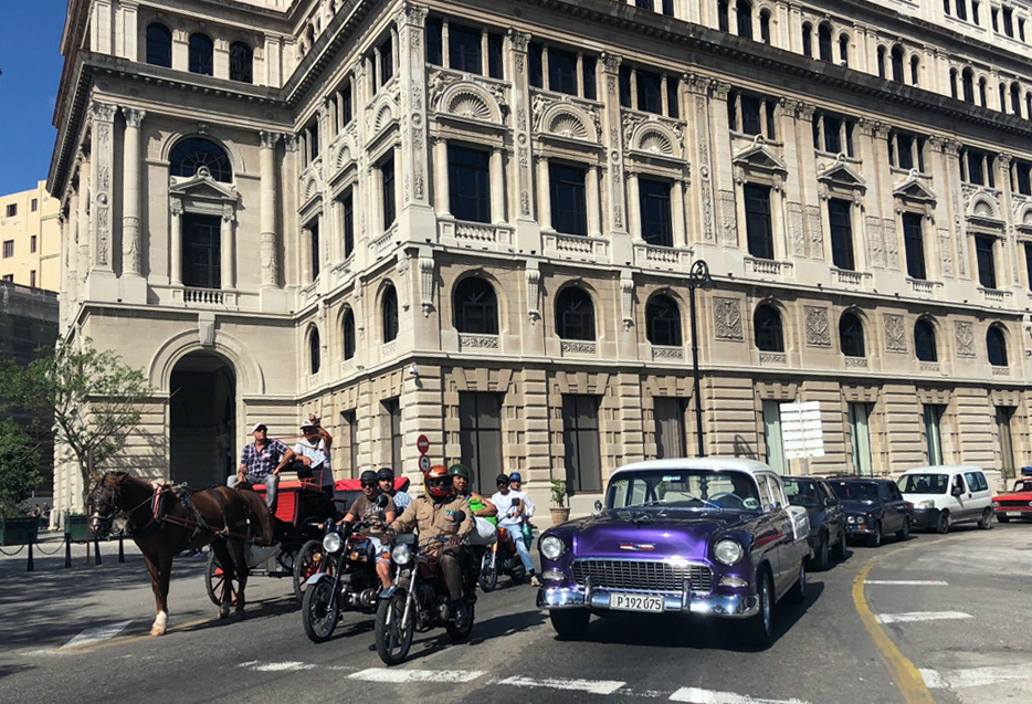 Motorcycles and 1950s cars share the streets with horse-drawn carts in Havana.