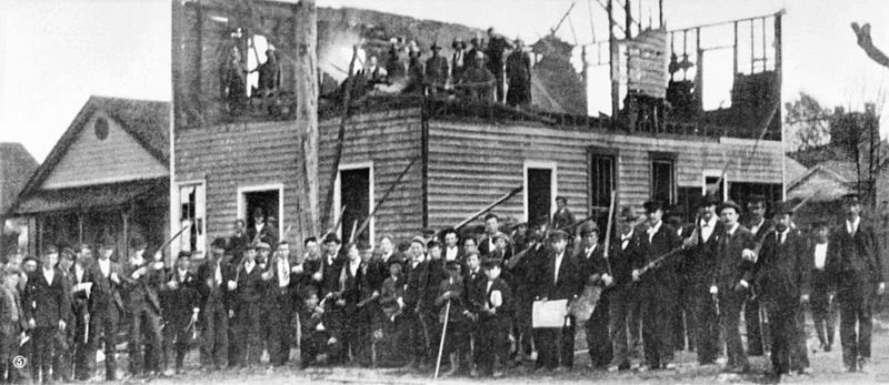 Armed white vigilantes posing in front of the burned newspaper office of a black-owned paper, The Wilmington Daily Record, in 1898.